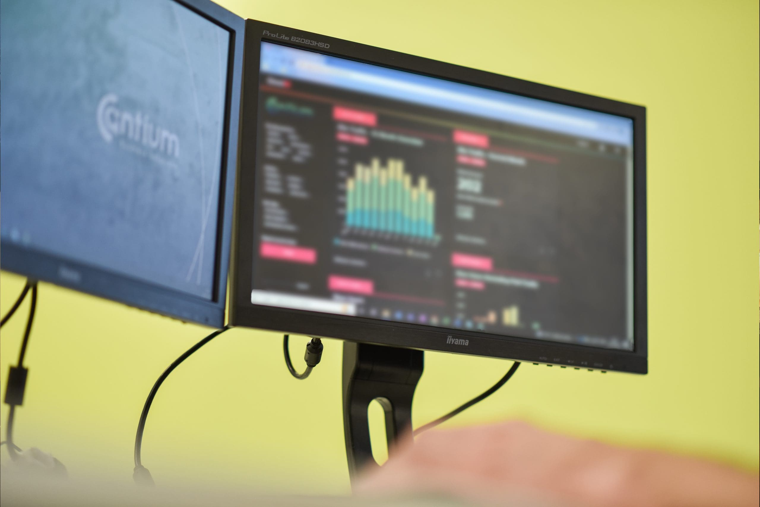 Photograph of two desktop monitors, one showing an analytics dashboard.