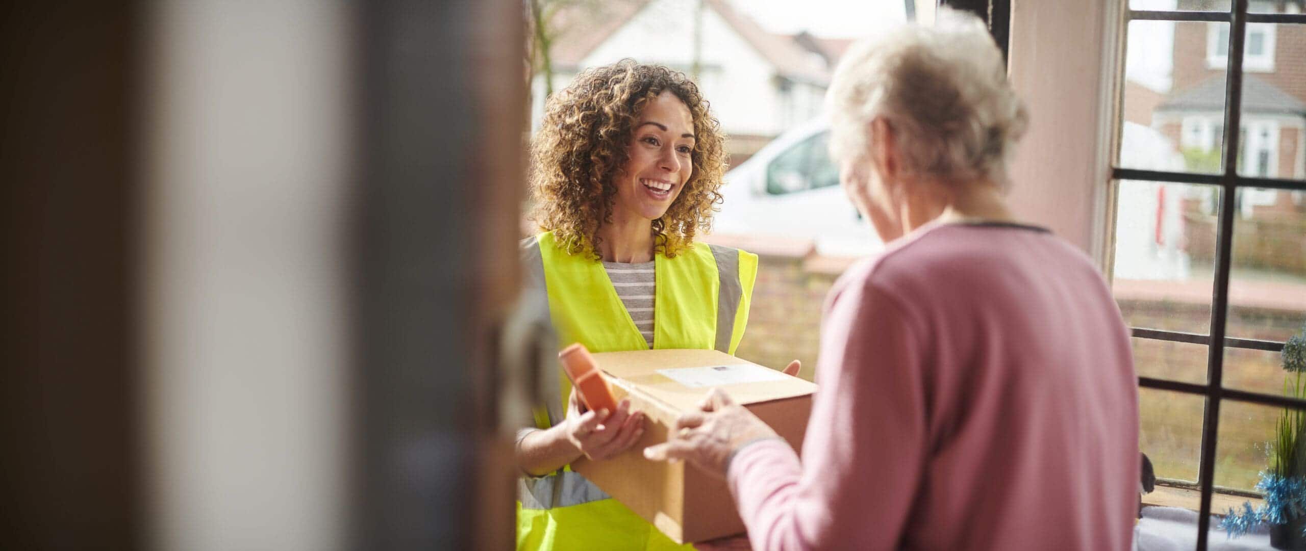 Photograph of a delivery driver making a device delivery to an elderly person's home to bridge the digital divide
